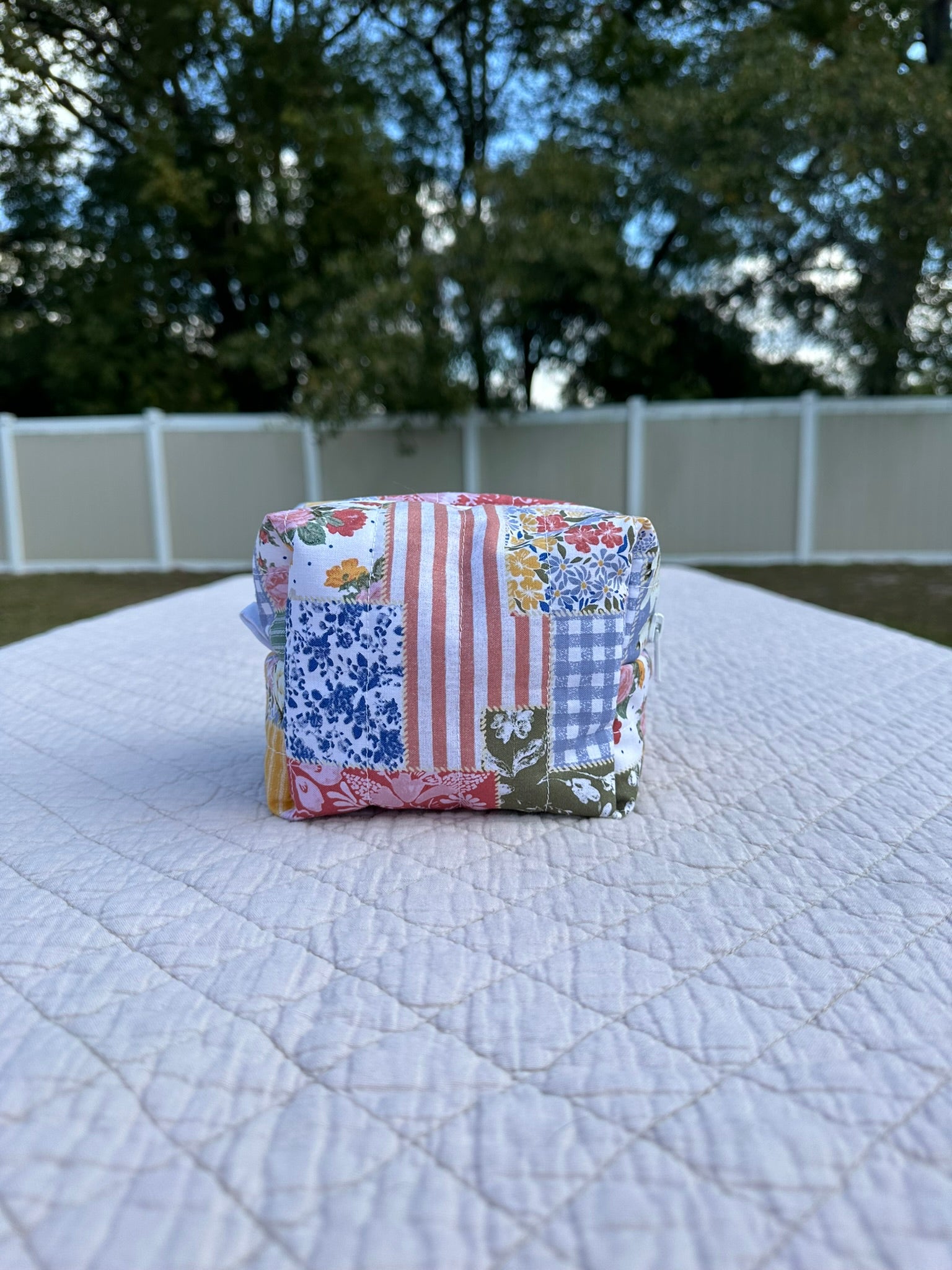 Stack of colorful fabric cups on a white surface with trees in the background